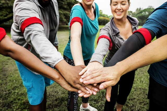 Group of people putting their hands in the center of the group.